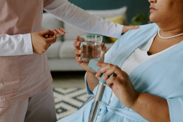 istock Hispanic Nurse Helping Elderly Person with Taking Pills 2158201910