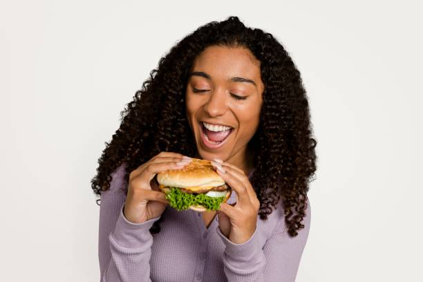 istock Happy woman eating a hamburger 2158203027