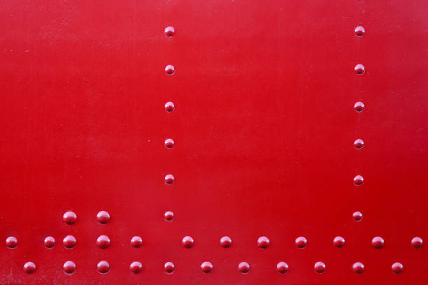 Closeup of a riveted with button-head rivets metal plate painted in red - part of a vintage locomotive - as an industrial background