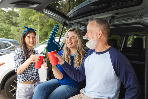 istock Friends sitting and drinking in the car boot at a tailgate party 2158204619