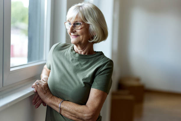 istock Smiling mature woman looking through window from her new apartment. 2158204742