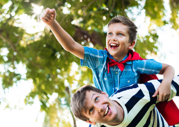 Superhero boy flying on the back of his dad