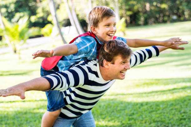Superhero boy flying on the back of his dad