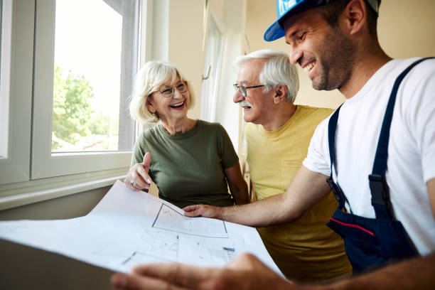 istock Happy senior couple analyzing housing plans with manual worker. 2158205038