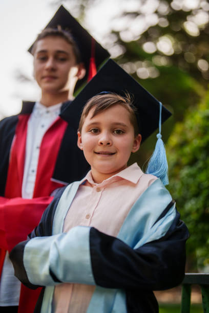 istock Sibling boys are wearing graduation gowns and mortarboards. 2158207976