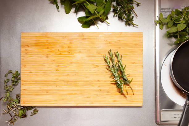 Healthy vegan food, eating, cooking, blogging background. Empty rustic cutting board with mushrooms, tomatoes, lettuce, vegetables on white kitchen with wooden table, kitchenware and utensils.