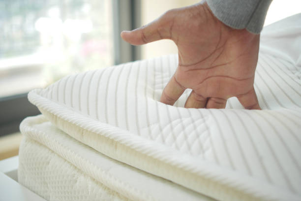 istock Hand touching and pressing orthopedic mattress on bed. 2158209560