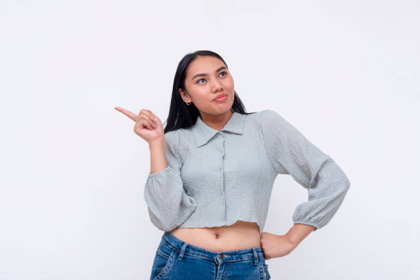 istock A thoughtful Asian woman pointing up, appearing to be finalizing thoughts or decisions, isolated over white. 2158210679