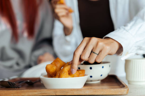 A close-up shot of hands reaching for fried snacks during brunch, emphasizing a shared meal experience in a casual setting.