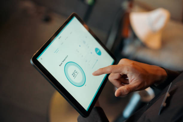 hostel staff use digital tablet to check and adjust temperature settings in a modern, stylish interior with ambient lighting - huisverwarming fotos stockfoto's en -beelden