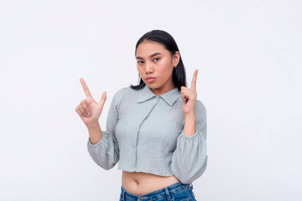 istock A young asian woman making double finger gun gestures. Isolated on a white background. 2158212041