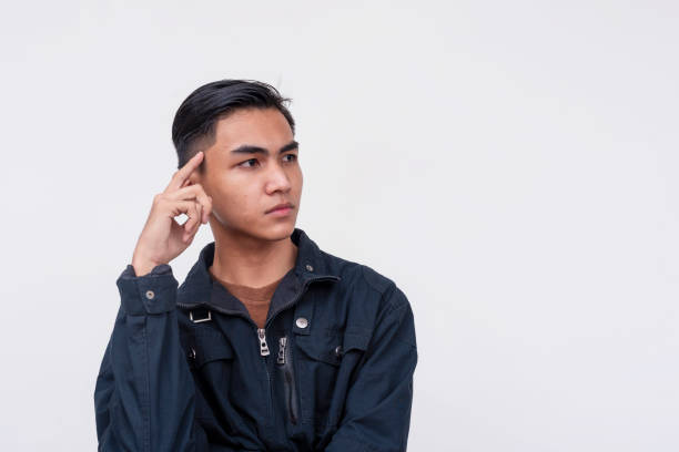 A young asian man thinking about ideas. Brainstorming for new concepts. Looking serious and focused. Isolated on a white background.
