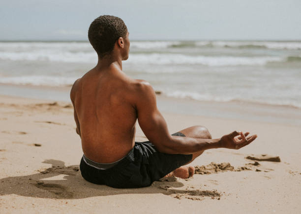 istock Black man meditating at the beach 2158212779