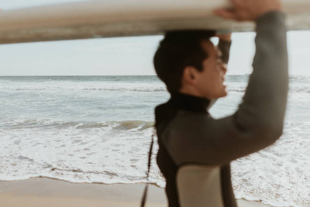 istock Surfer carrying a surfboard at the beach 2158212954