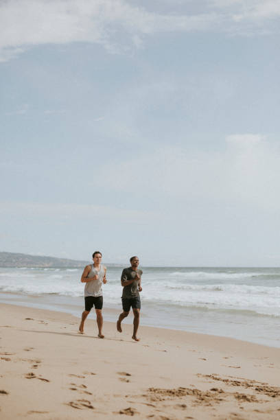 istock Happy friends jogging at the beach together 2158213000