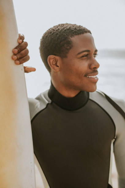 istock Black man standing by the surfboard 2158213955