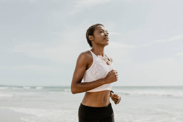 istock Black woman jogging on the beach 2158214300