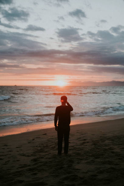 istock Man watching the sunset on the beach 2158214411
