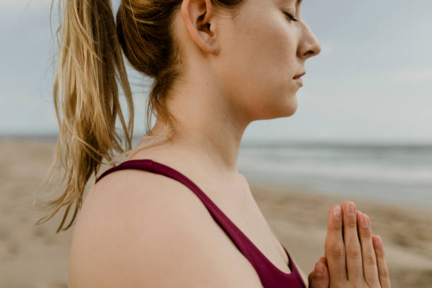 istock Woman practicing yoga on the beach 2158214544