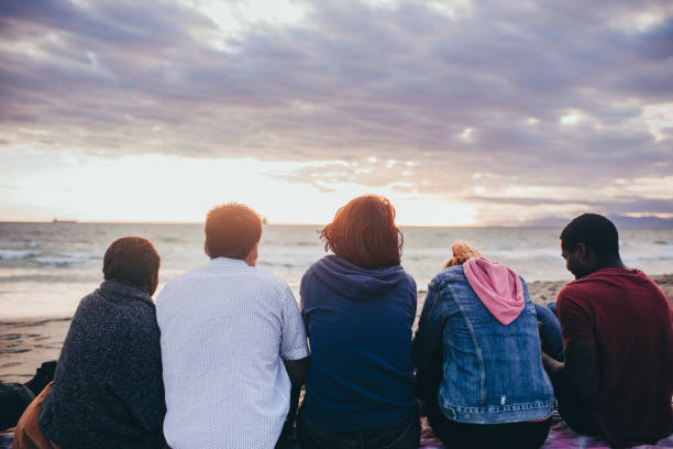 istock Happy friends sitting together on the beach 2158214567