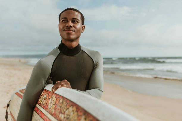 istock Cheerful man with a surfboard at the beach 2158214740