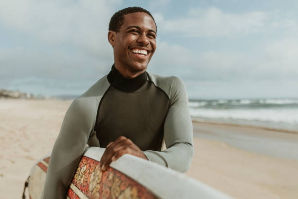 istock Cheerful man with a surfboard at the beach 2158214755