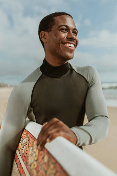 istock Cheerful man with a surfboard at the beach 2158214758
