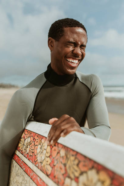 istock Cheerful man with a surfboard at the beach 2158214765