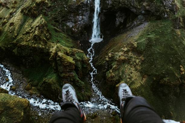 istock Pair of legs with a view of a waterfall 2158215721