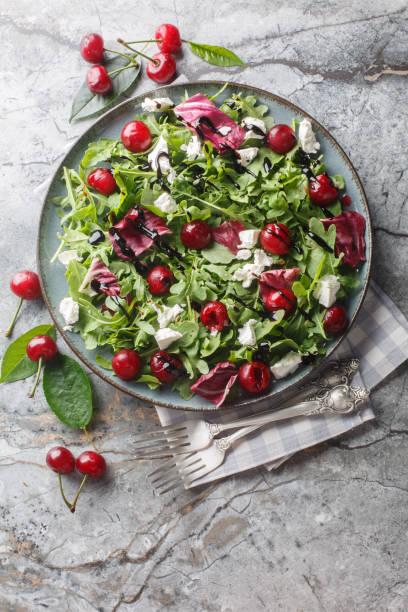 istock Pickled cherry, goat cheese and rocket salad with balsamic sauce close-up in a plate. Vertical top view 2158215893