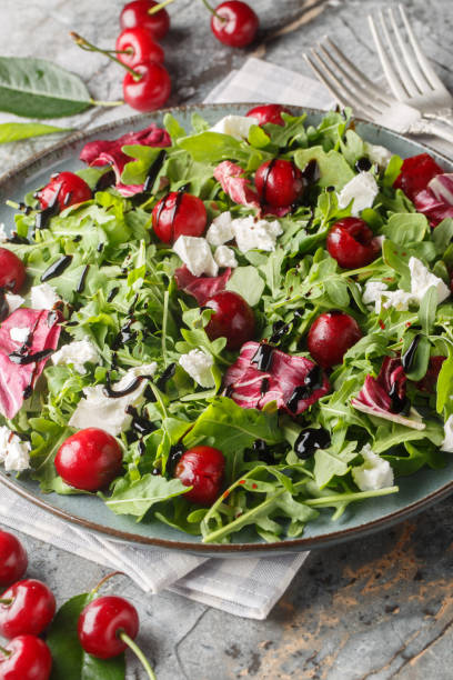 istock Pickled cherry, goat cheese and rocket salad with balsamic sauce close-up in a plate. Vertical 2158215938