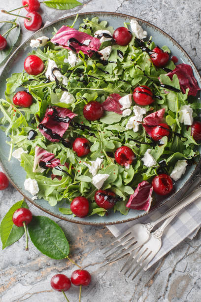 istock Cherry salad with pickled berries, arugula, radicchio and feta cheese dressed with balsamic dressing close-up in a plate. Vertical top view 2158215949