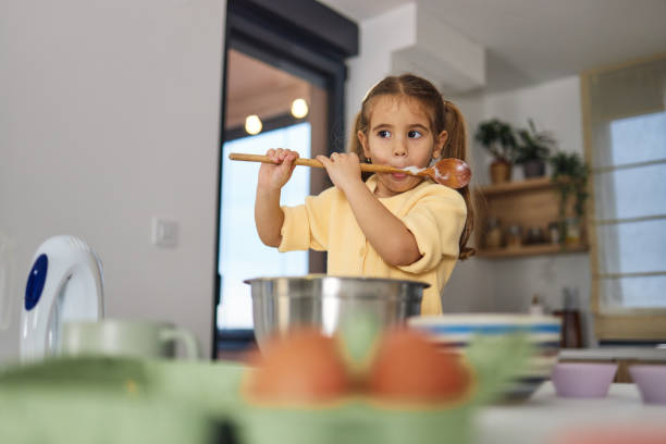 istock Young girl stands at the kitchen table making cakes 2158219772