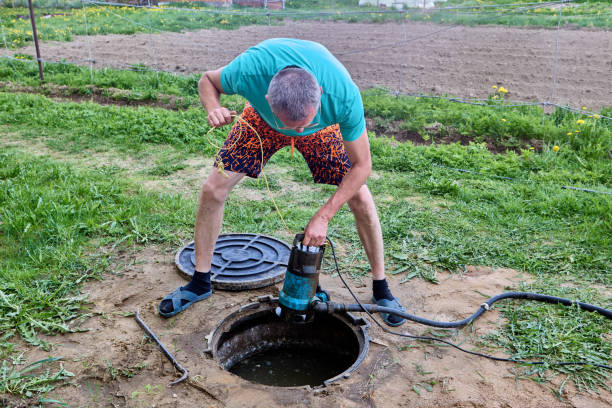istock Man lowers submersible wastewater pump into  septic tank. 2158221992