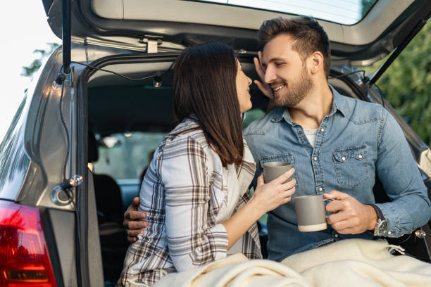 istock Couple Sips Coffee and Laughs in Car Trunk 2158222108