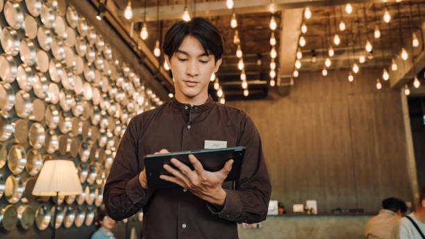 istock Hostel Staff Use digital tablet to Check and Adjust Temperature Settings in a Modern, Stylish Interior with Ambient Lighting 2158222922