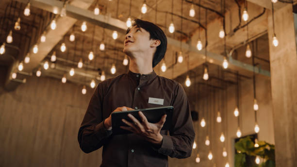 Hostel Staff Use digital tablet to Check and Adjust Energy  in a Modern, Stylish Interior with Ambient Lighting