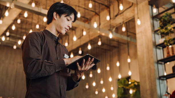 istock Hostel Staff Use digital tablet to Check and Adjust Temperature Settings in a Modern, Stylish Interior with Ambient Lighting 2158222933