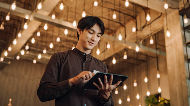 istock Hostel Staff Use digital tablet to Check and Adjust Energy  in a Modern, Stylish Interior with Ambient Lighting 2158222942