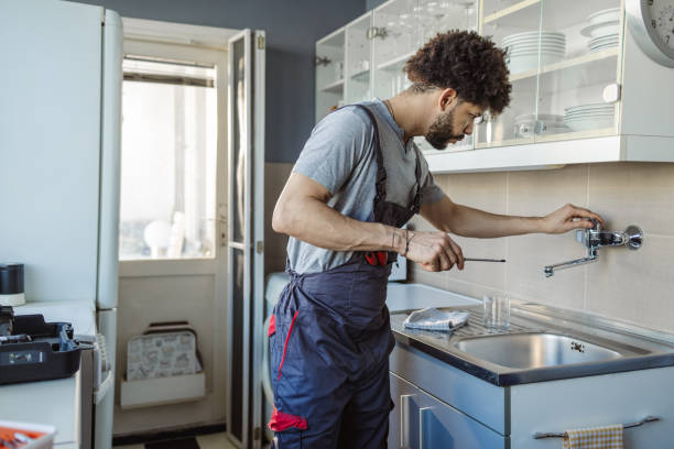 istock Hispanic plumber fixing a leak in the kitchen sink at the customer's home 2158223559
