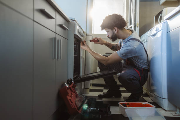 istock Young Latin worker repairing the oven in the kitchen 2158223617