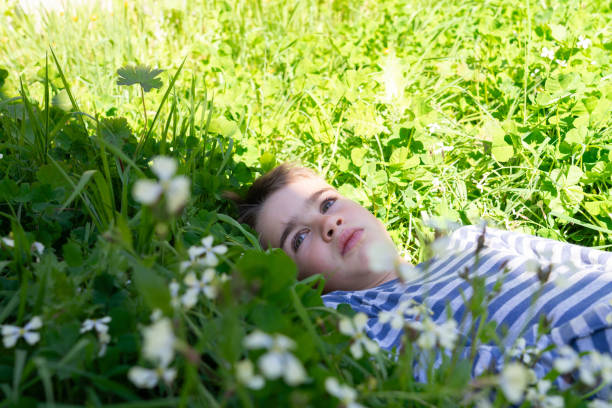 Portrait of an attractive teenager boy holding his smartphone with his hand and taking a selfie of himself against a green leaves. Using smart phone technology outdoors to take photos