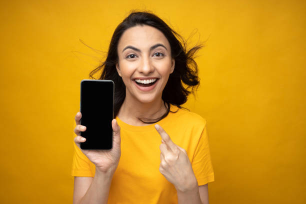 istock Young woman showing device screen isolate yellow background stock photo 2158224841