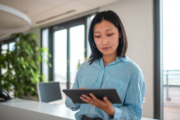 istock Asian Businesswoman Analyzing Data on Tablet in Office 2158225511
