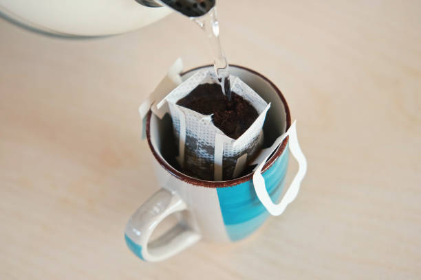 istock Drip bag fresh coffee. Pouring hot water into blue cup with drip coffee bag. Instant freshly brewed cup of ground coffee. Coffee Trend. Quick way to brew using paper filter. The process of brewing 2158225881
