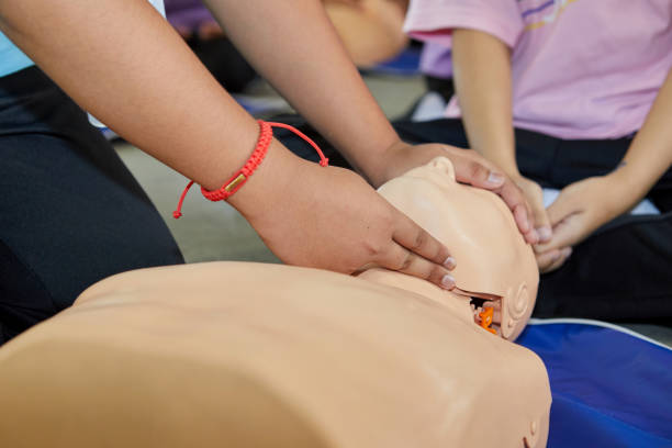 Cropped hands CPR First Aid training with CPR dummy in the classroom