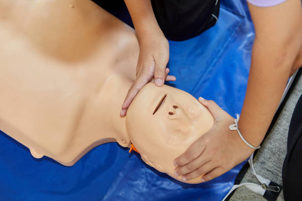 istock Cropped hands CPR First Aid training with CPR dummy in the classroom 2158226356