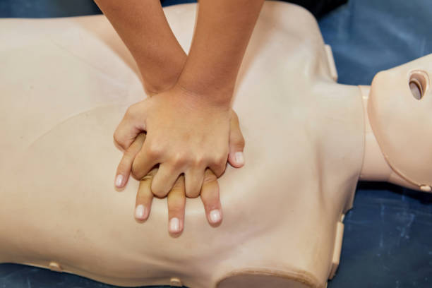 istock Cropped hands CPR First Aid training with CPR dummy in the classroom 2158226361