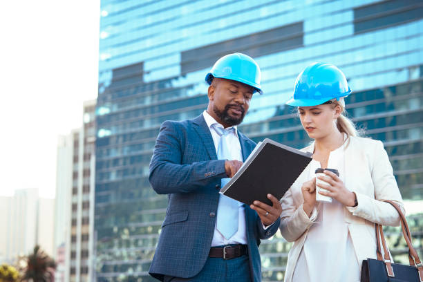 istock Colleges in hard hats discussing their new building plan 2158226992