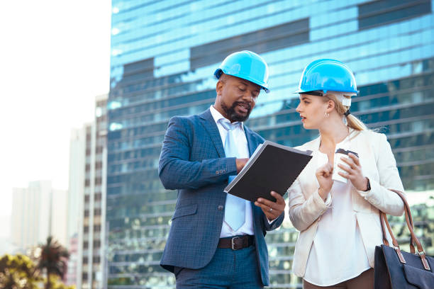 istock Colleges in hard hats discussing their new building plan 2158227008